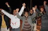 リビア北東部ムサイドで、革命勝利を訴え両手を上げるリビア人男性ら＝２２日夜（共同）